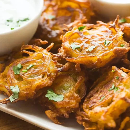 Close-up of crunchy onion fritters garnished with fresh cilantro, perfect for dipping.