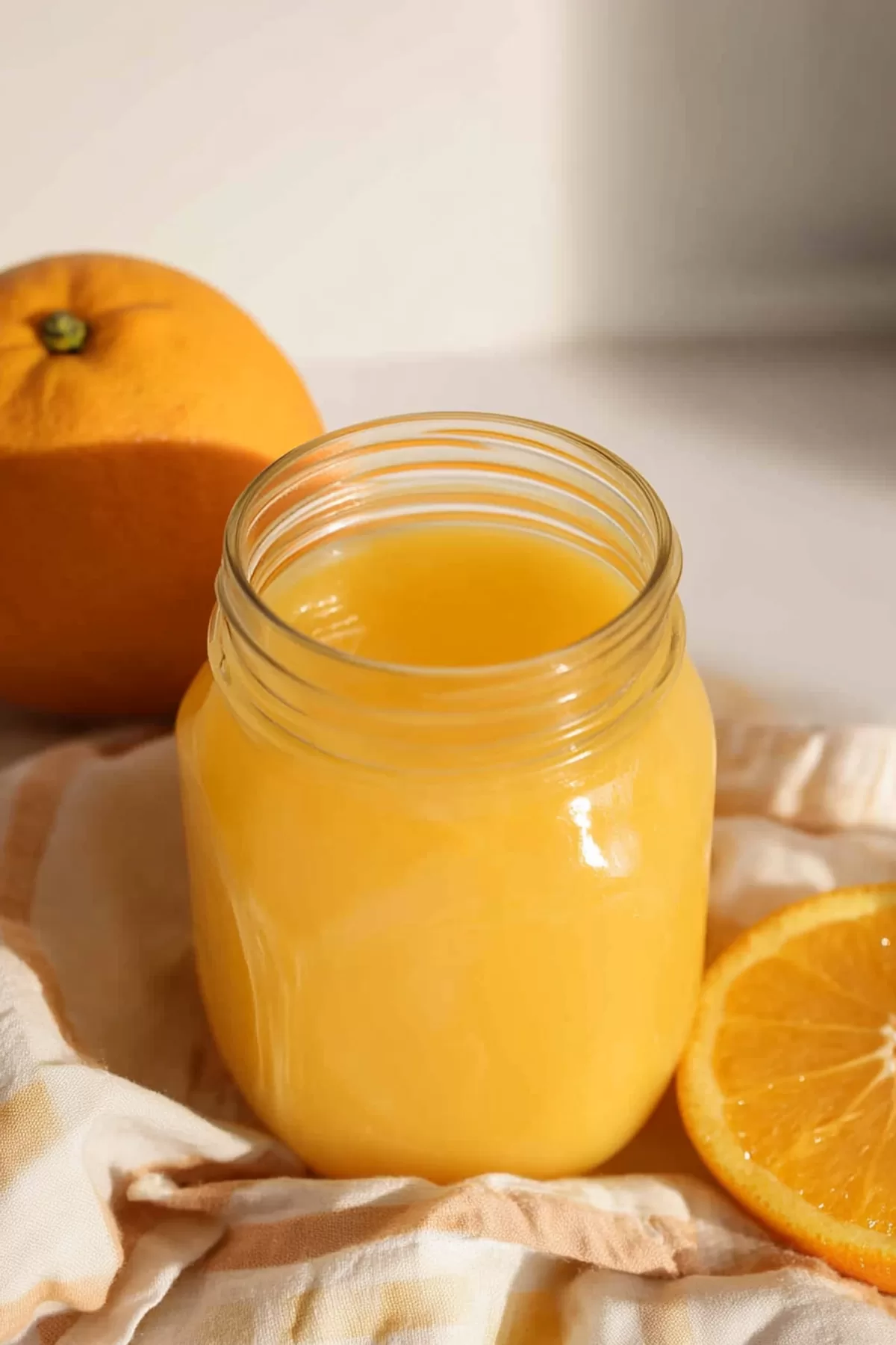 A mason jar filled with a creamy, orange-hued drink, topped with a slice of fresh orange.