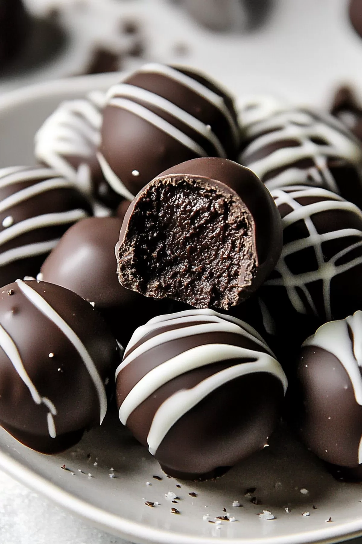 Delicious chocolate-covered truffles arranged on a white plate.