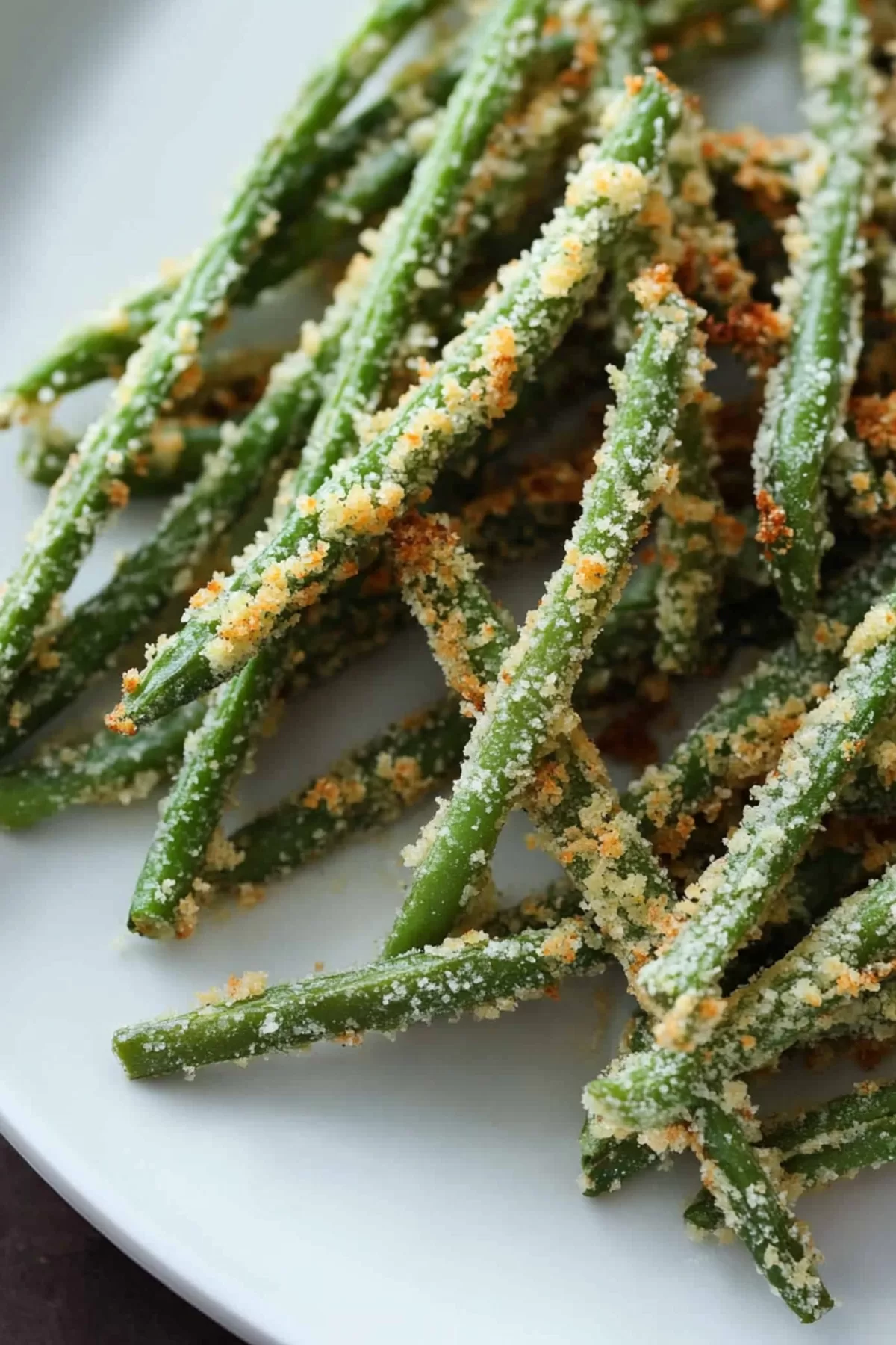 A serving plate filled with crispy green bean fries, garnished with a sprinkle of sea salt.