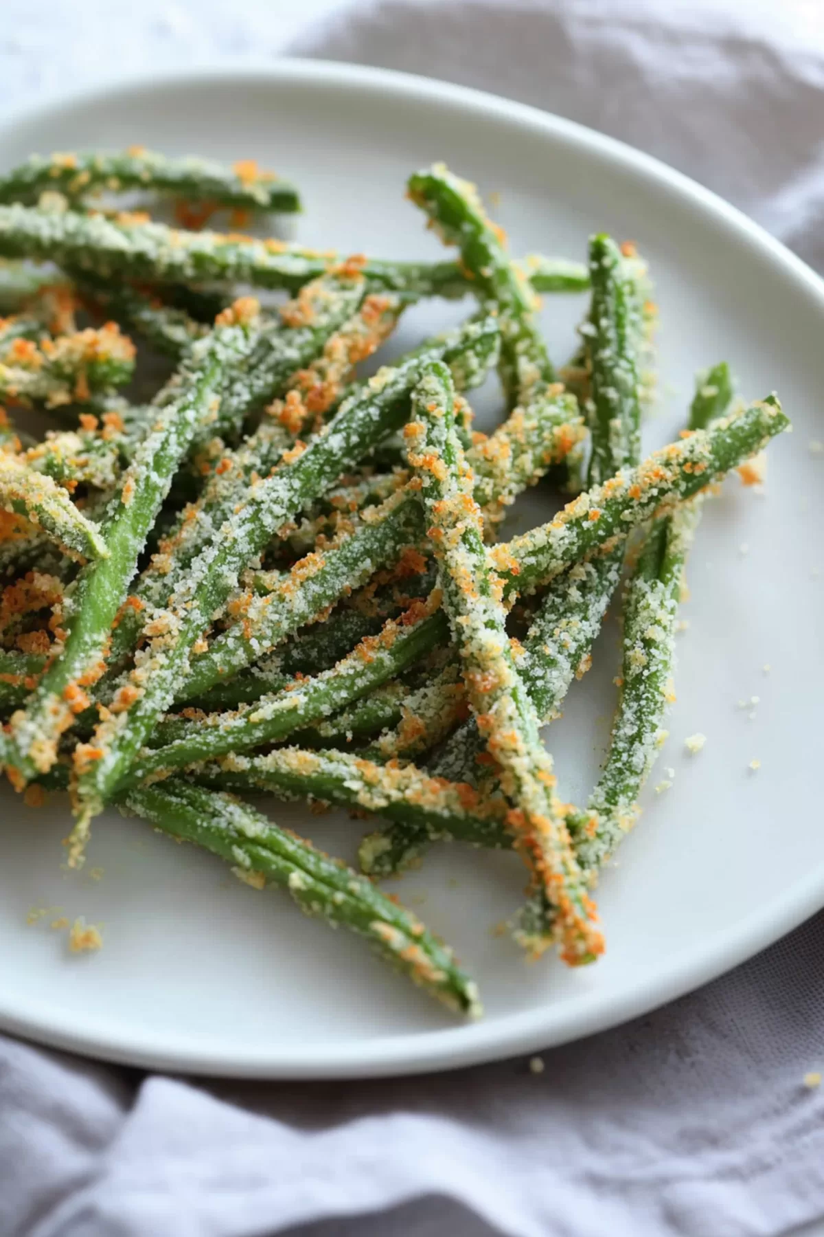 Golden-brown green bean fries fresh from the oven, showcasing their crunchy texture on a parchment-lined tray.