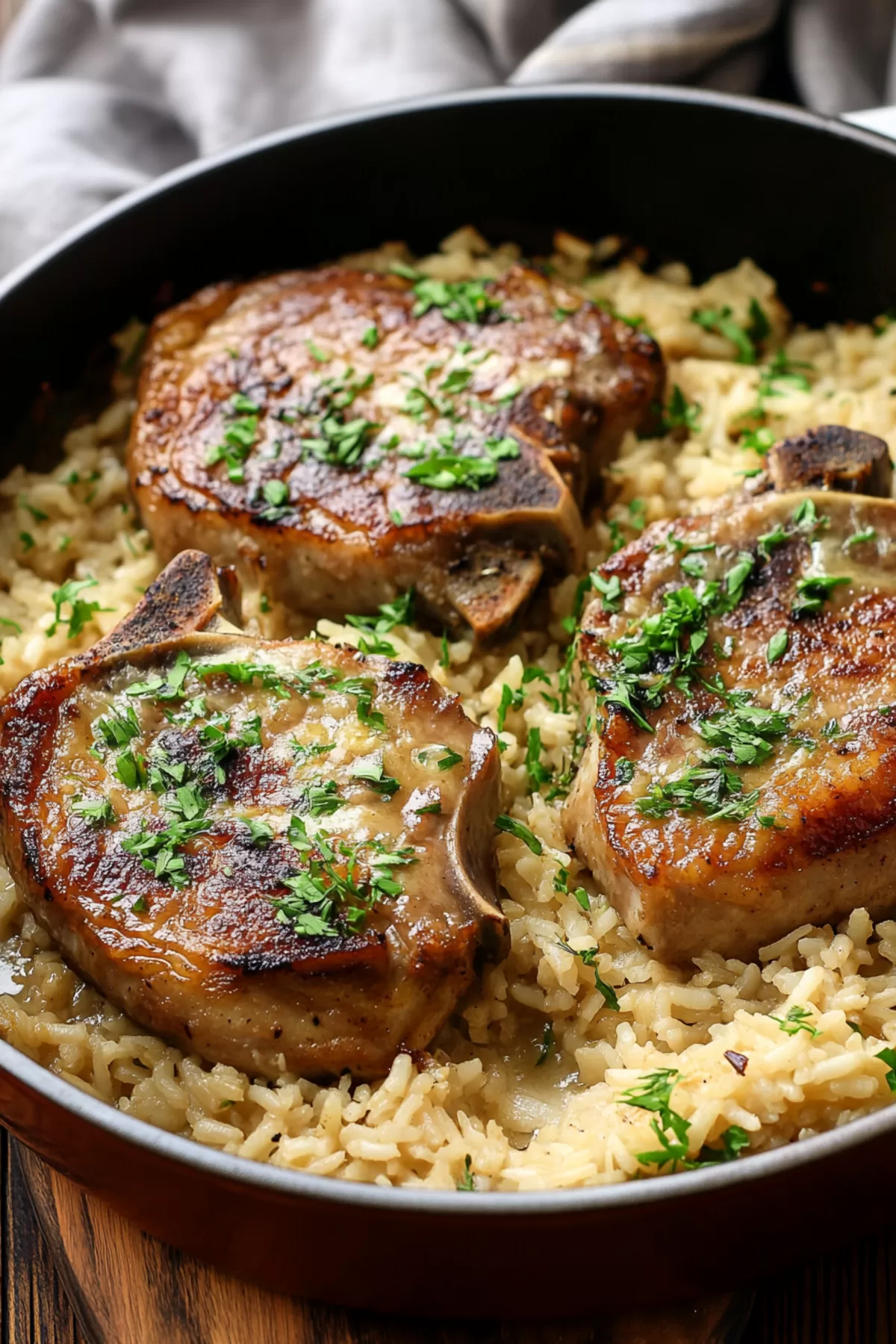 Close-up of a baked dish showcasing juicy pork chops layered over fluffy, flavorful rice.