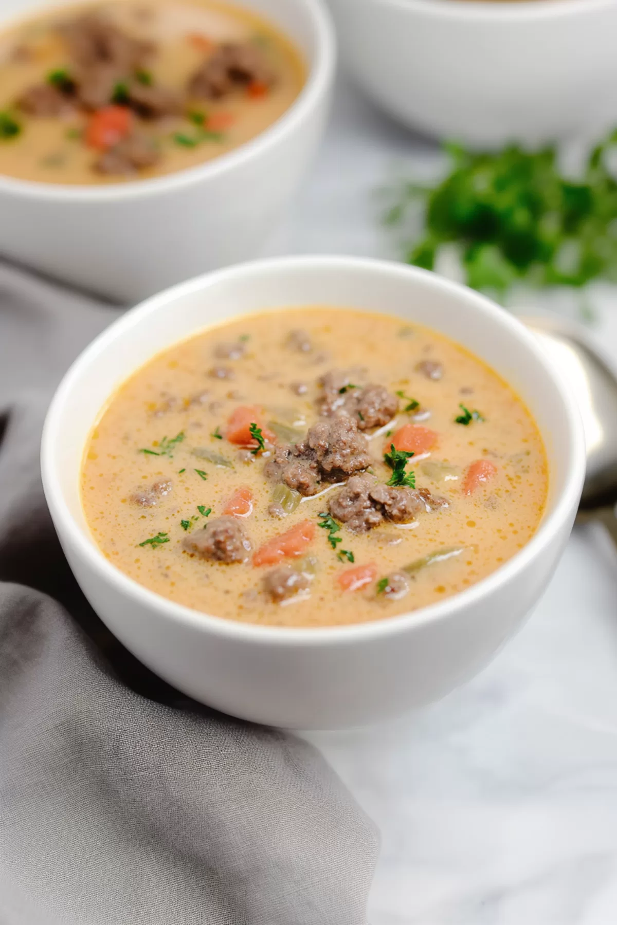 Warm soup served in a white bowl with a garnish of shredded cheddar and herbs for a cozy meal.