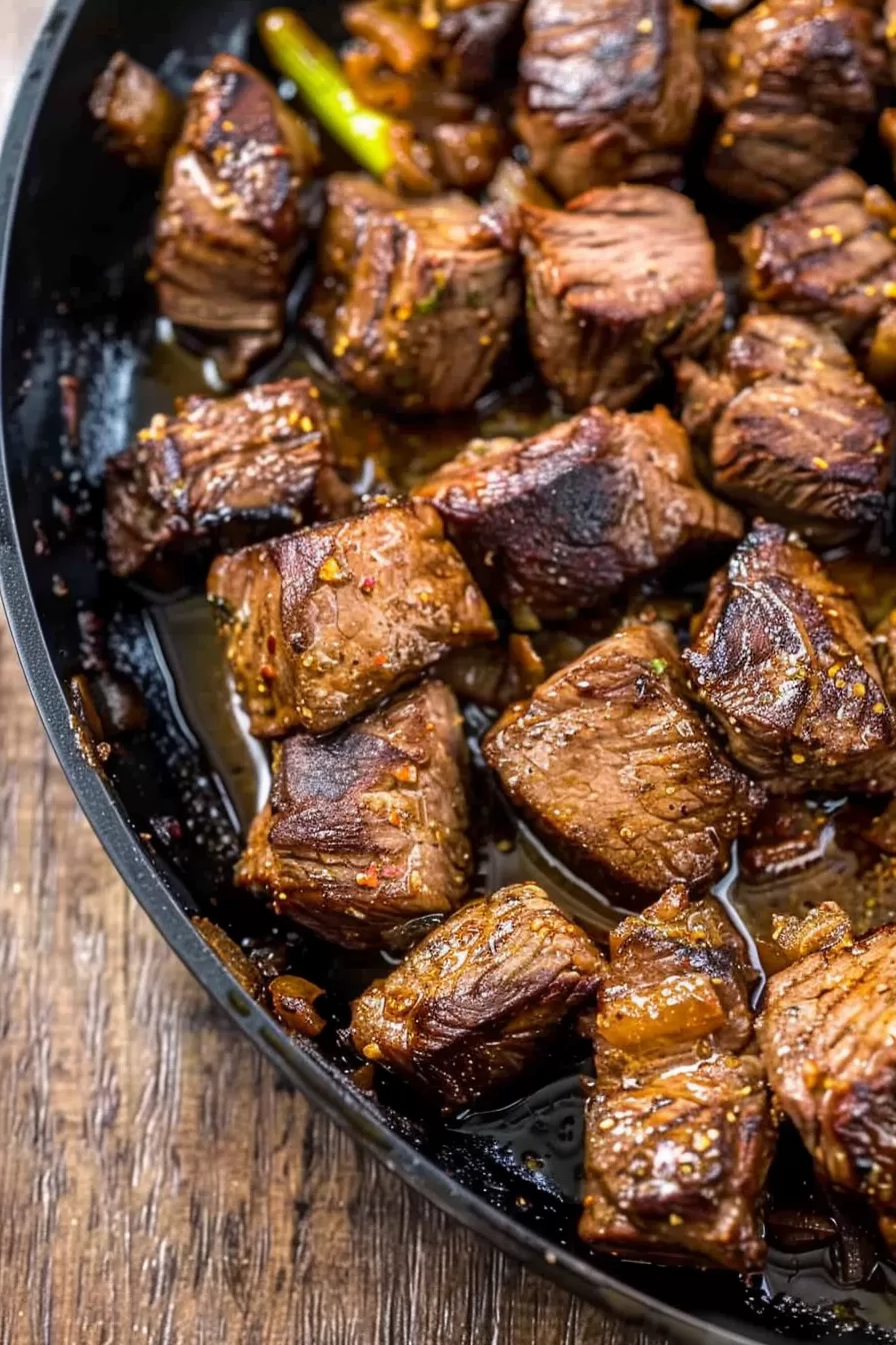 Sizzling steak bites in a buttery sauce, ready to serve as a flavorful appetizer.