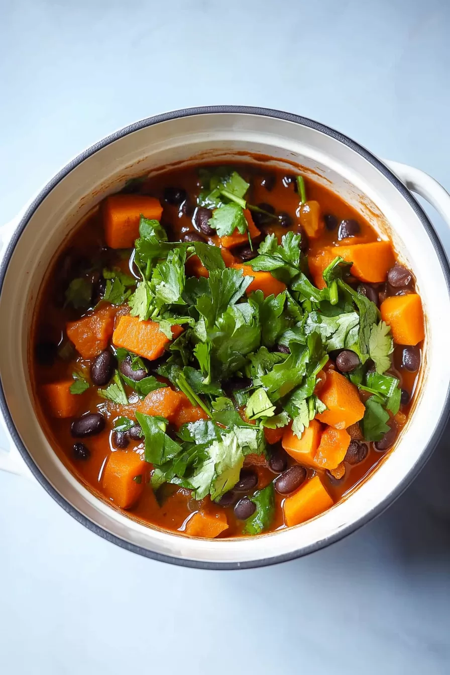 Overhead view of a comforting bowl of soup, surrounded by fresh ingredients like sweet potatoes and cilantro.