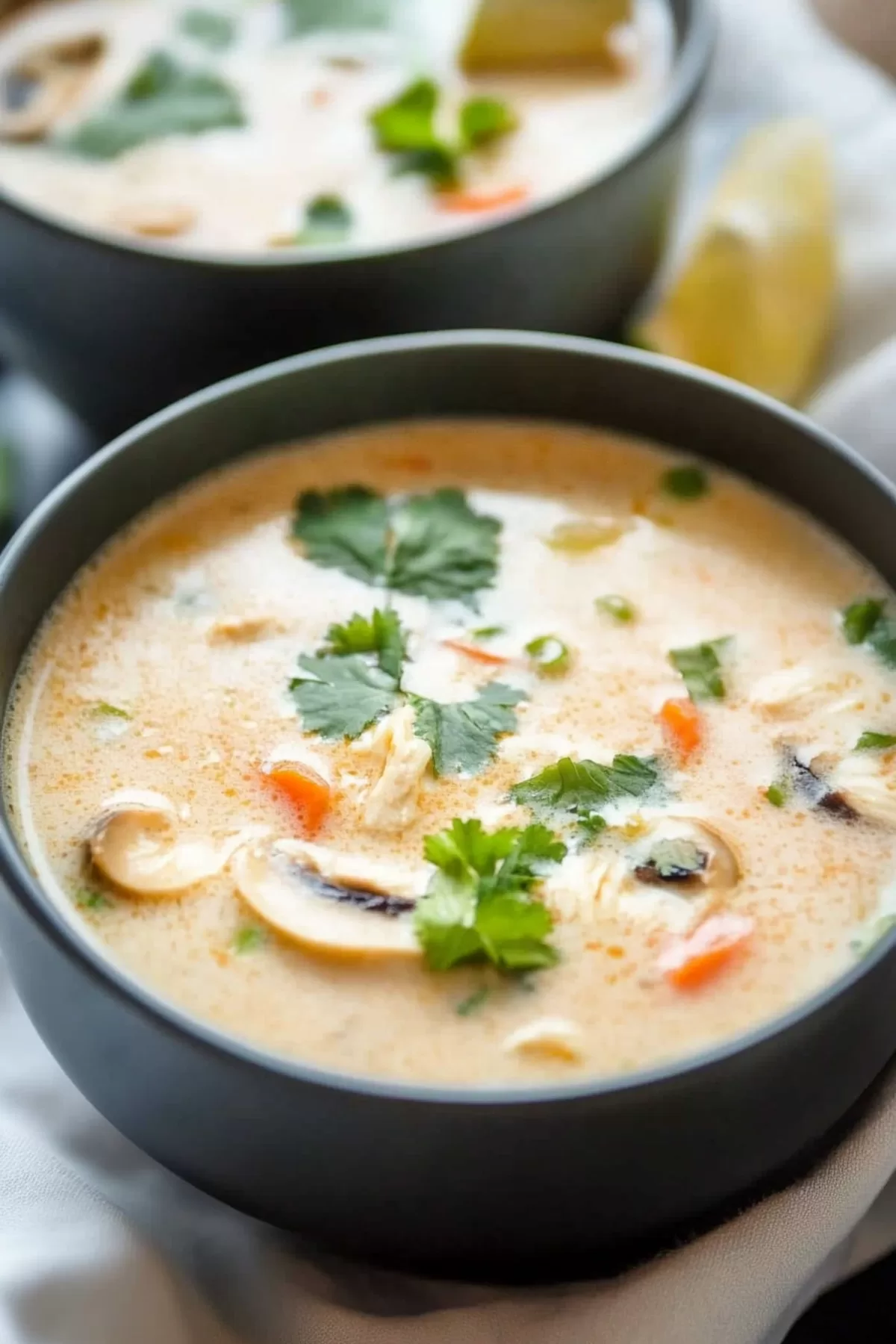 A vibrant and fragrant soup served with a side of lime and chili, showcasing its rich, creamy texture.