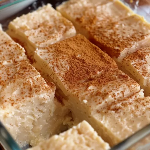 Traditional coconut dessert squares with a creamy consistency and golden cinnamon topping.