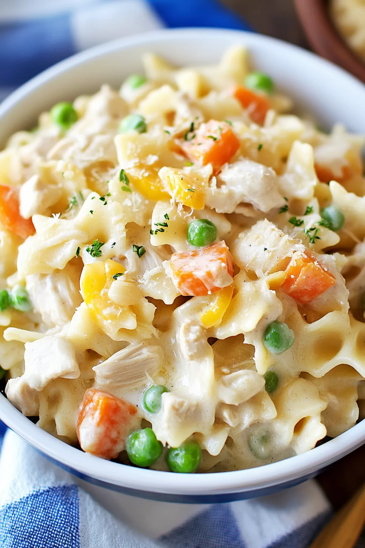 Close-up of a spoon scooping a hearty serving of creamy pasta and tender chicken.