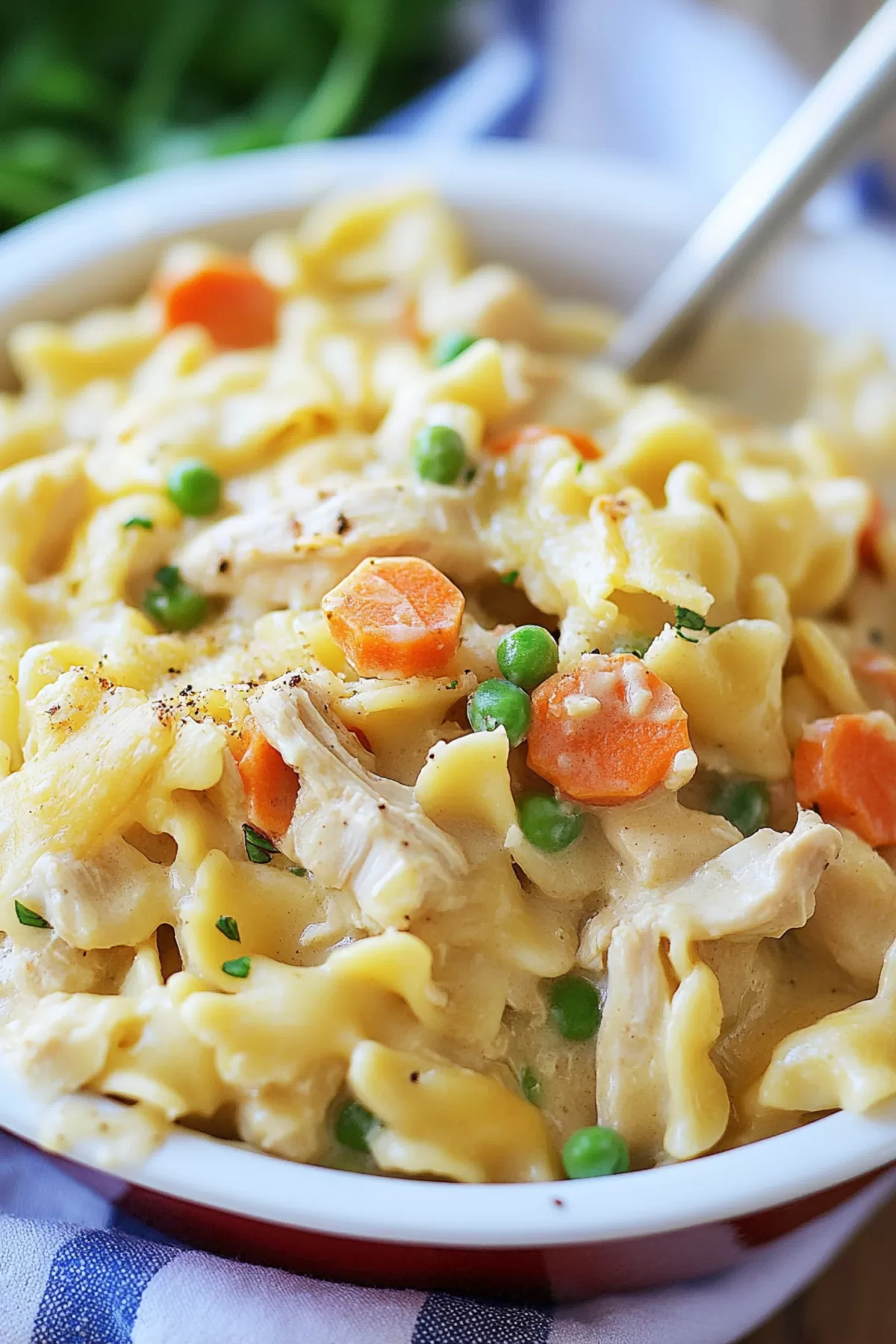 A plate of creamy pasta with a golden sauce and scattered peas and carrots.