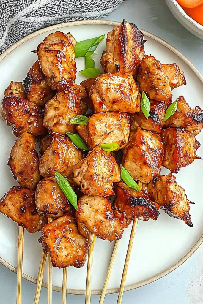 Juicy grilled chicken skewers glazed with a rich, savory sauce and garnished with fresh green onions.