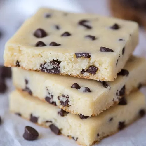 Close-up of a single chocolate chip shortbread cookie with a bite taken out, revealing a tender crumb.