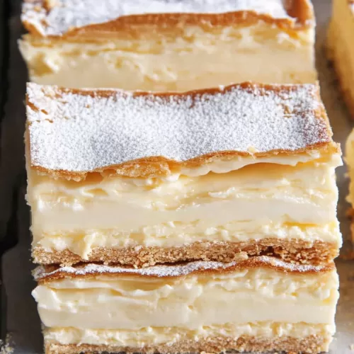 A tray of vanilla slices showcasing multiple flaky layers and rich custard filling.