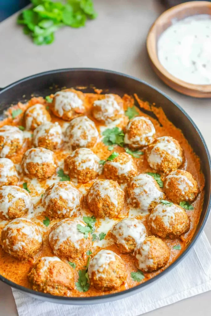 Savory coconut curry meatballs simmered in a rich, creamy sauce garnished with fresh cilantro.