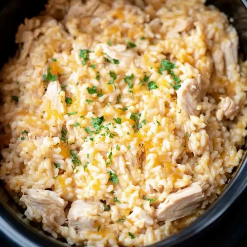 Slow-cooked chicken and rice with melted cheese and a sprinkle of parsley for a hearty meal.