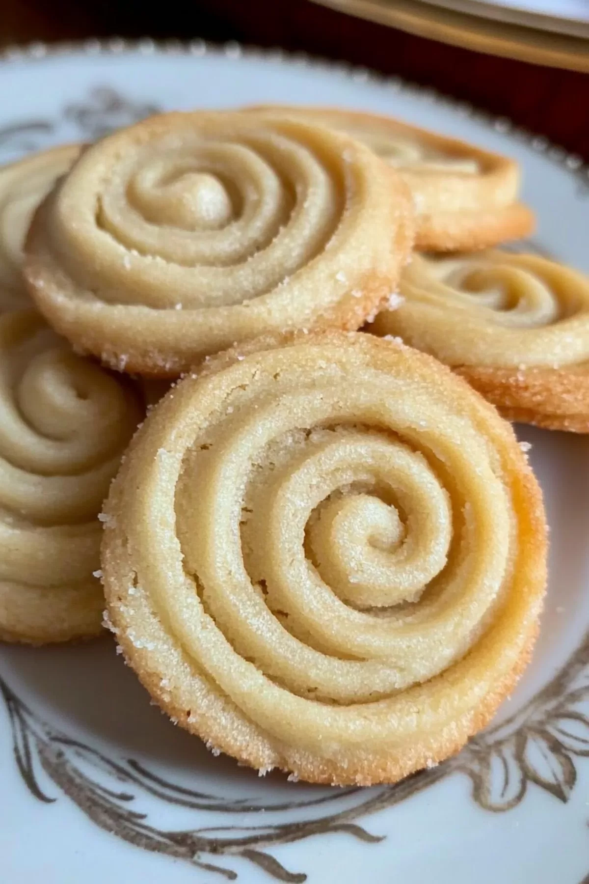 Close-up of buttery swirled cookies with a delicate golden crust arranged in a festive box.