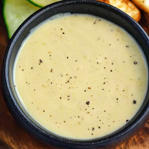 A small serving of Dijonnaise beside grilled vegetables and slices of toasted bread.