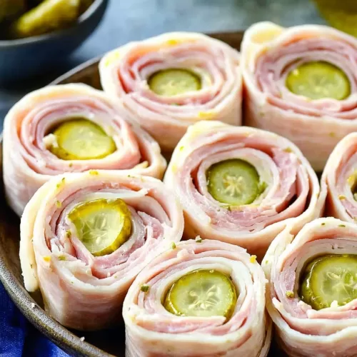 A delightful arrangement of ham pickle roll-ups on a rustic plate, featuring their colorful layers and savory appeal.