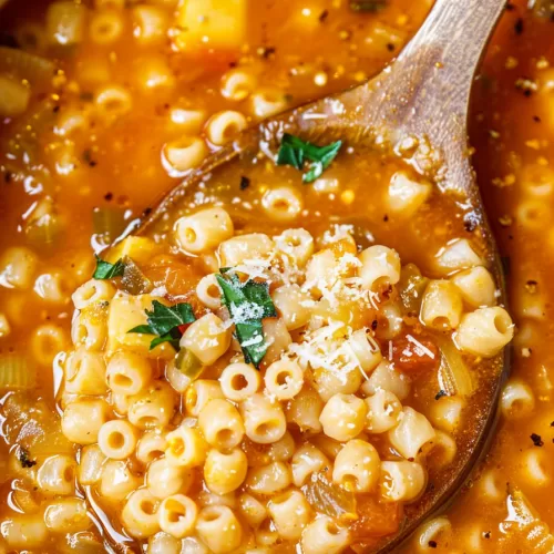 A spoonful of Italian Pastina Soup showing perfectly cooked ditalini pasta and a rich, flavorful broth topped with grated cheese and herbs.