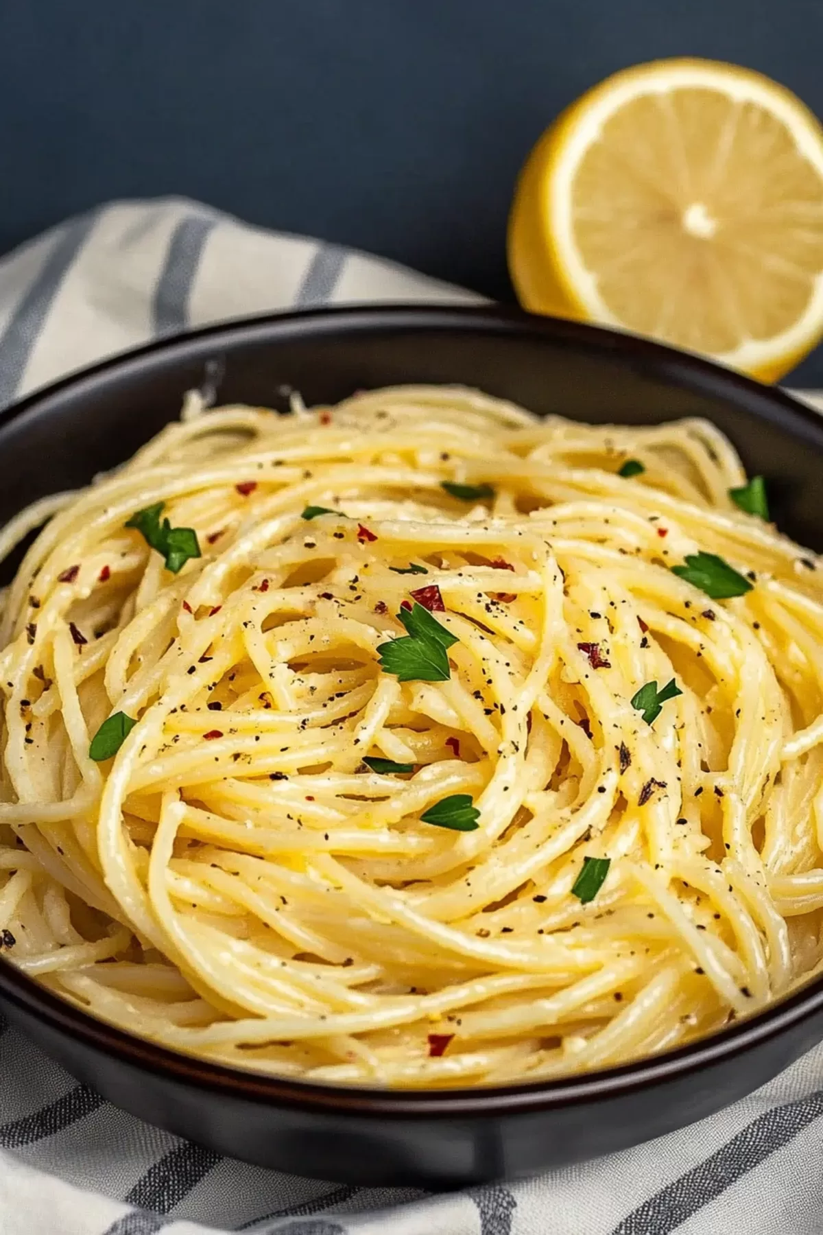 A bowl of spaghetti tossed in a luscious lemon butter sauce, sprinkled with cracked black pepper.