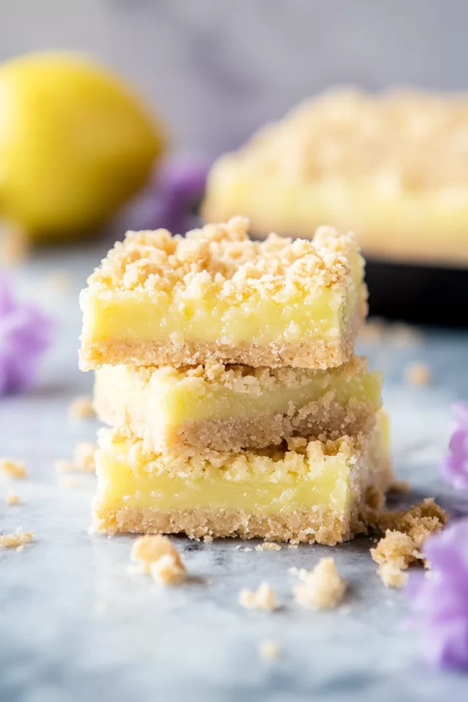 A stack of golden crumb-topped bars with a bright, creamy lemon filling.