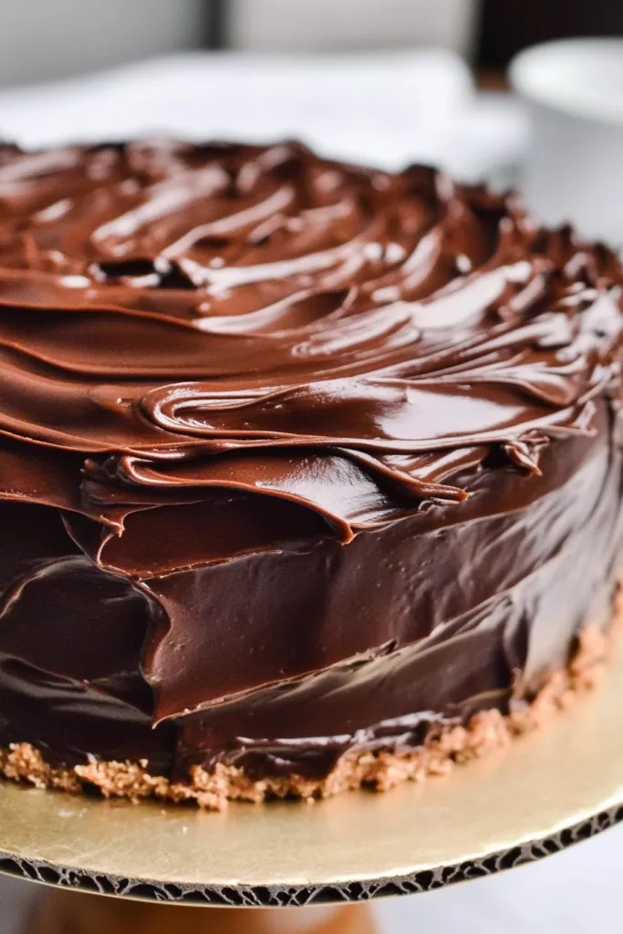 A rich chocolate cake topped with glossy, thick chocolate frosting.