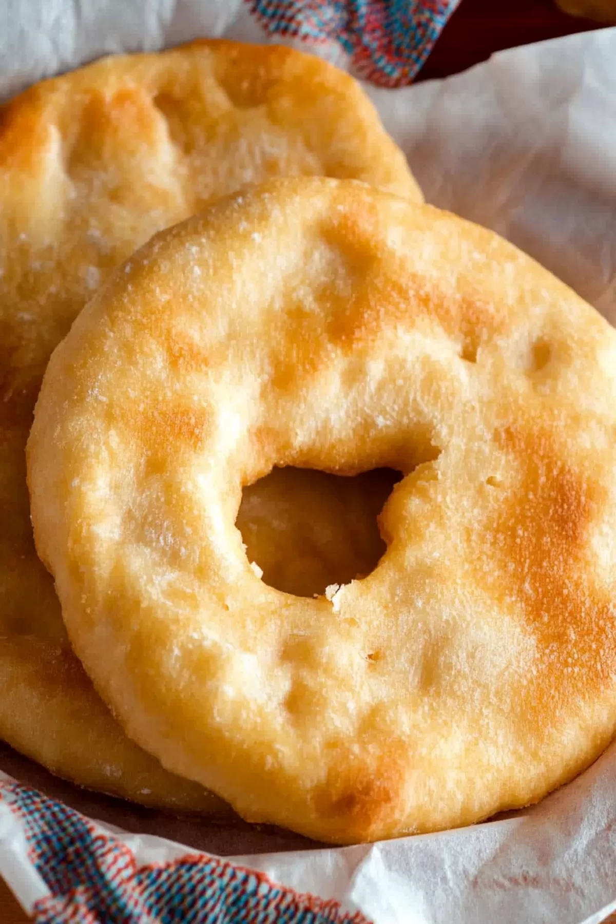 Freshly fried bread with a fluffy interior, arranged on a decorative cloth.