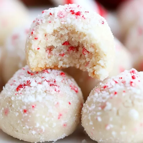 A bite-sized peppermint snowball cookie revealing its soft, crumbly interior with a touch of crushed peppermint candy.