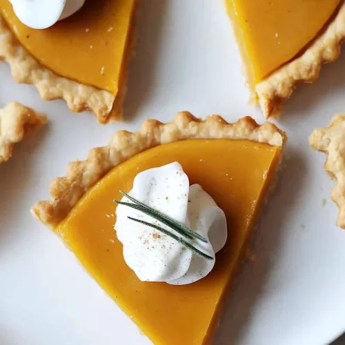 Individual servings of pumpkin-inspired cheese and crackers, styled with herb garnish on a plate.