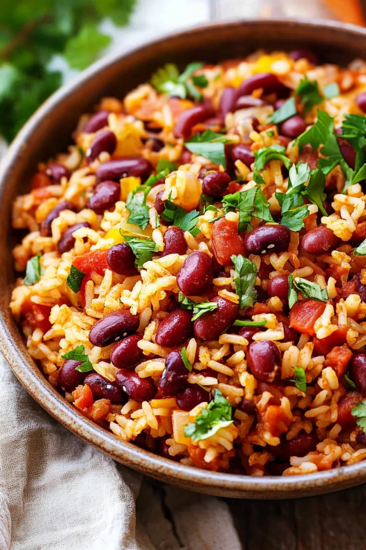 A hearty serving of Spanish rice and beans, topped with diced peppers and herbs, served in a rustic brown bowl.