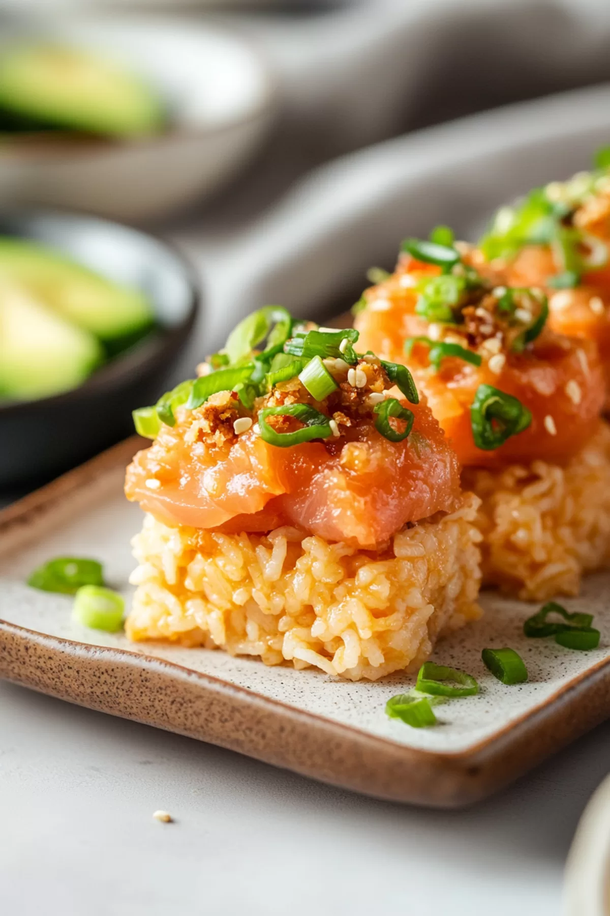 A beautifully arranged platter of spicy tuna crispy rice bites, showcasing vibrant toppings and a golden rice base.