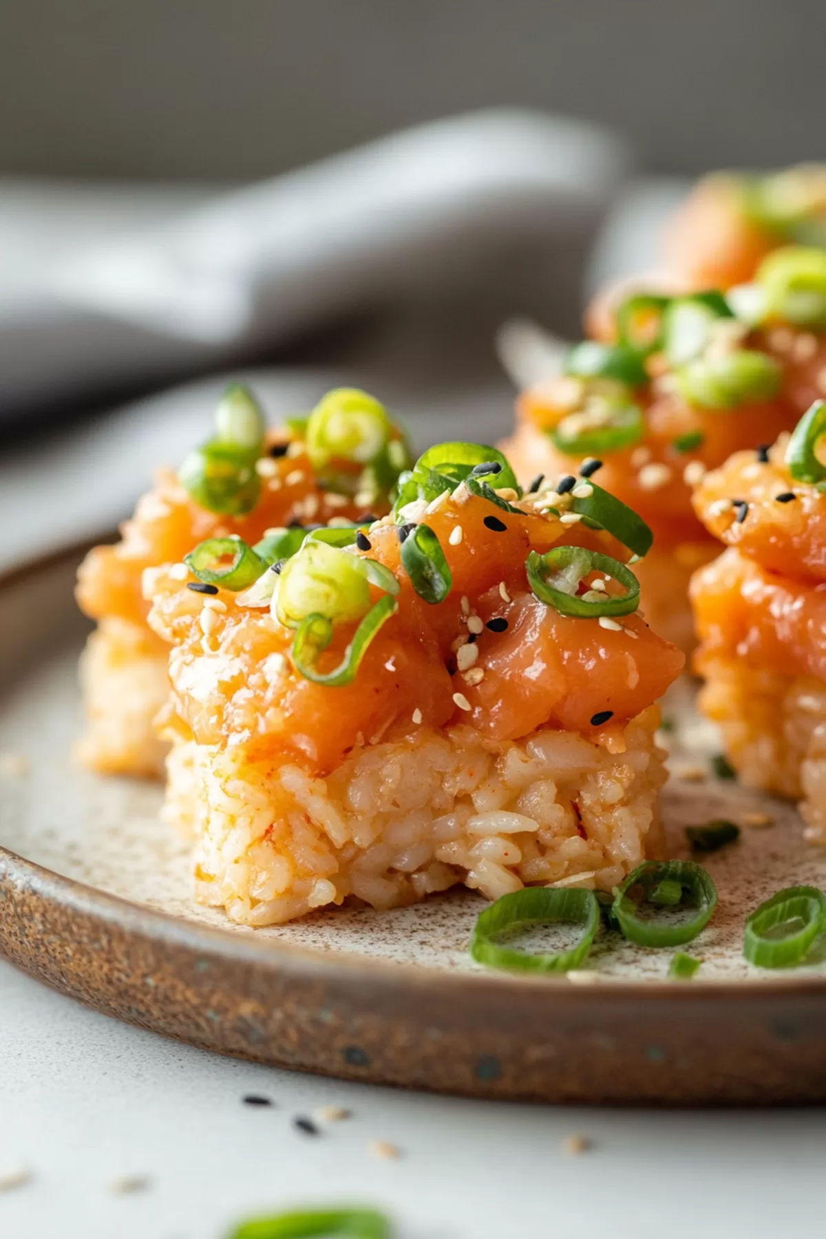 Spicy tuna crispy rice garnished with fresh green onions and sesame seeds, presented as a delicious appetizer.