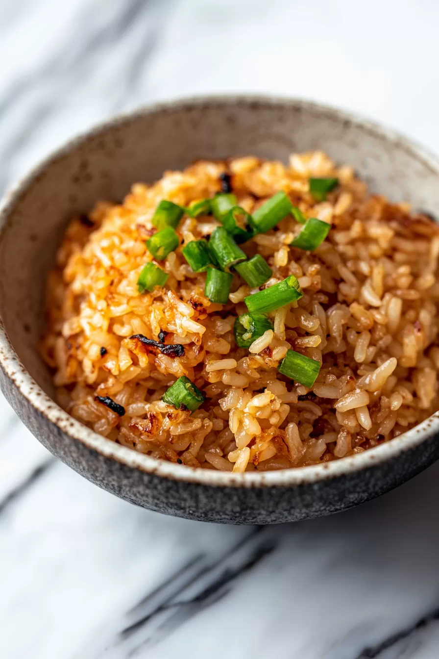 A bowl of savory rice with crispy bits and fresh green onion for a simple, comforting side dish.