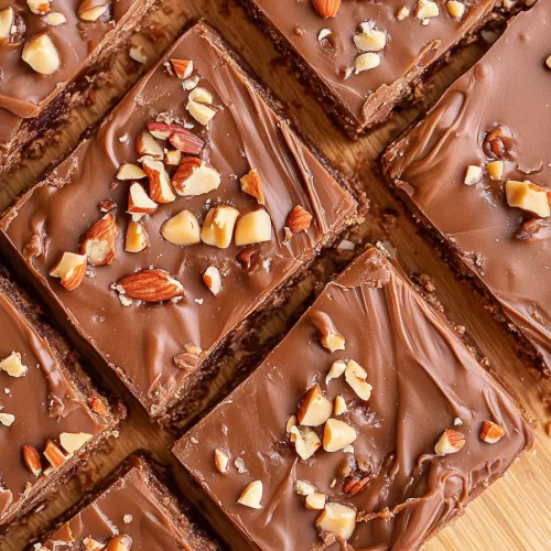 A close-up of rich chocolate fudge topped with chopped pecans and caramel swirls, ready to enjoy.