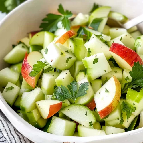 Close-up of a healthy apple cucumber salad with diced apples, cucumbers, and herbs, showing bright colors and fresh textures.