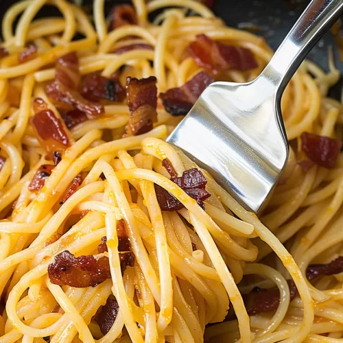 Freshly cooked spaghetti with bacon, coated in a rich sauce, garnished with herbs and served with a fork