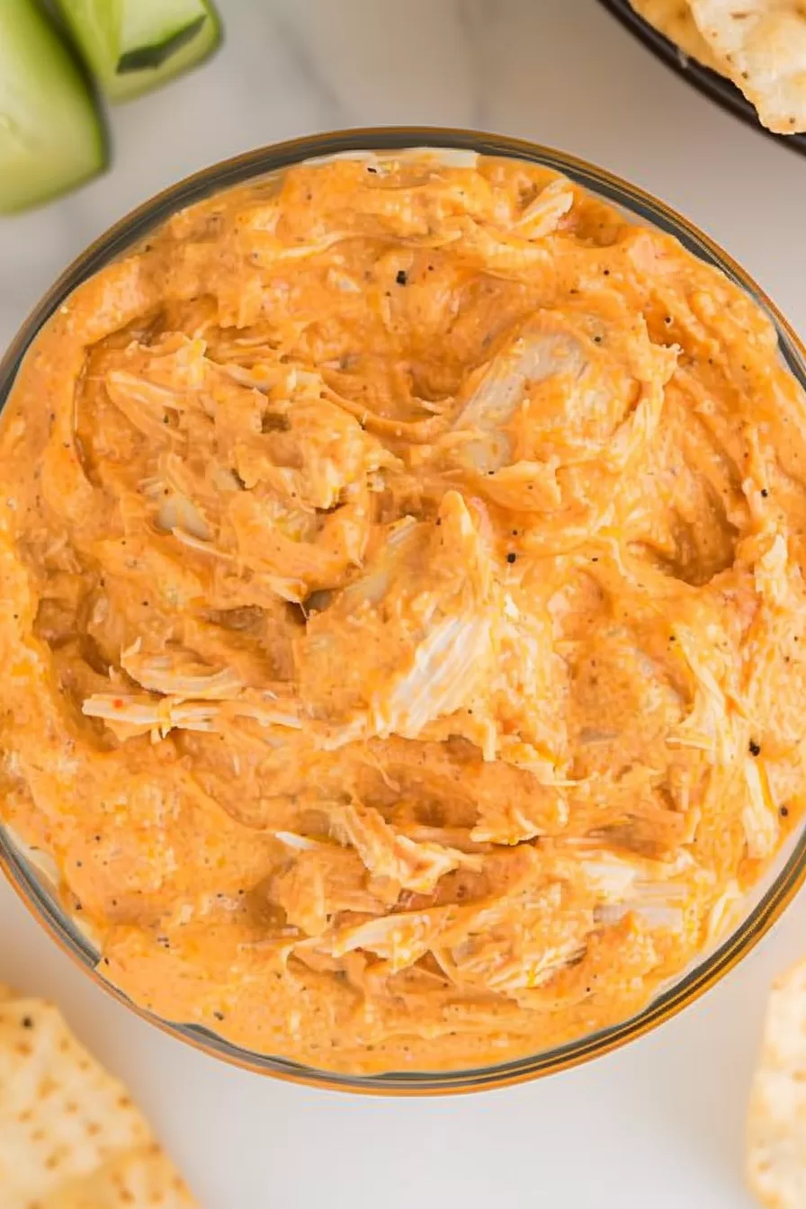 Close-up shot of creamy Buffalo Chicken Dip with tender shredded chicken, served in a glass bowl, surrounded by tortilla chips.