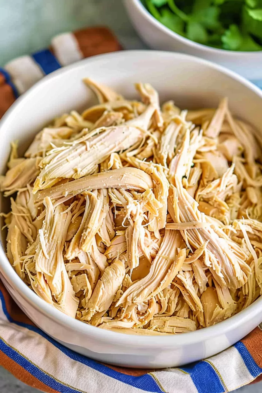 Simple and juicy shredded chicken breast in a bowl, prepared in a slow cooker for easy meal prep.