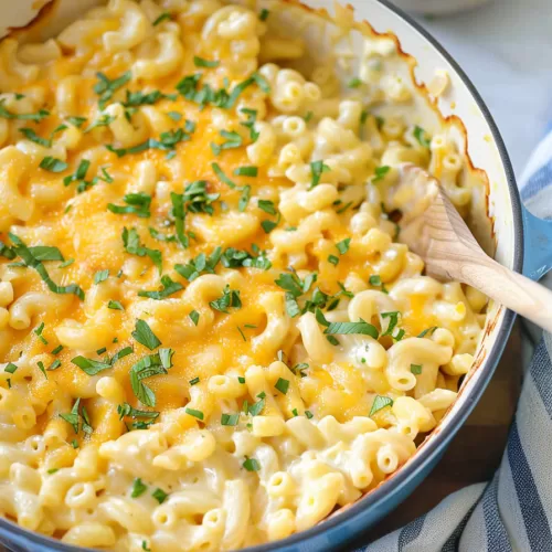 A baked dish of mac and cheese with a golden cheesy crust, garnished with fresh parsley, presented in a blue casserole dish.