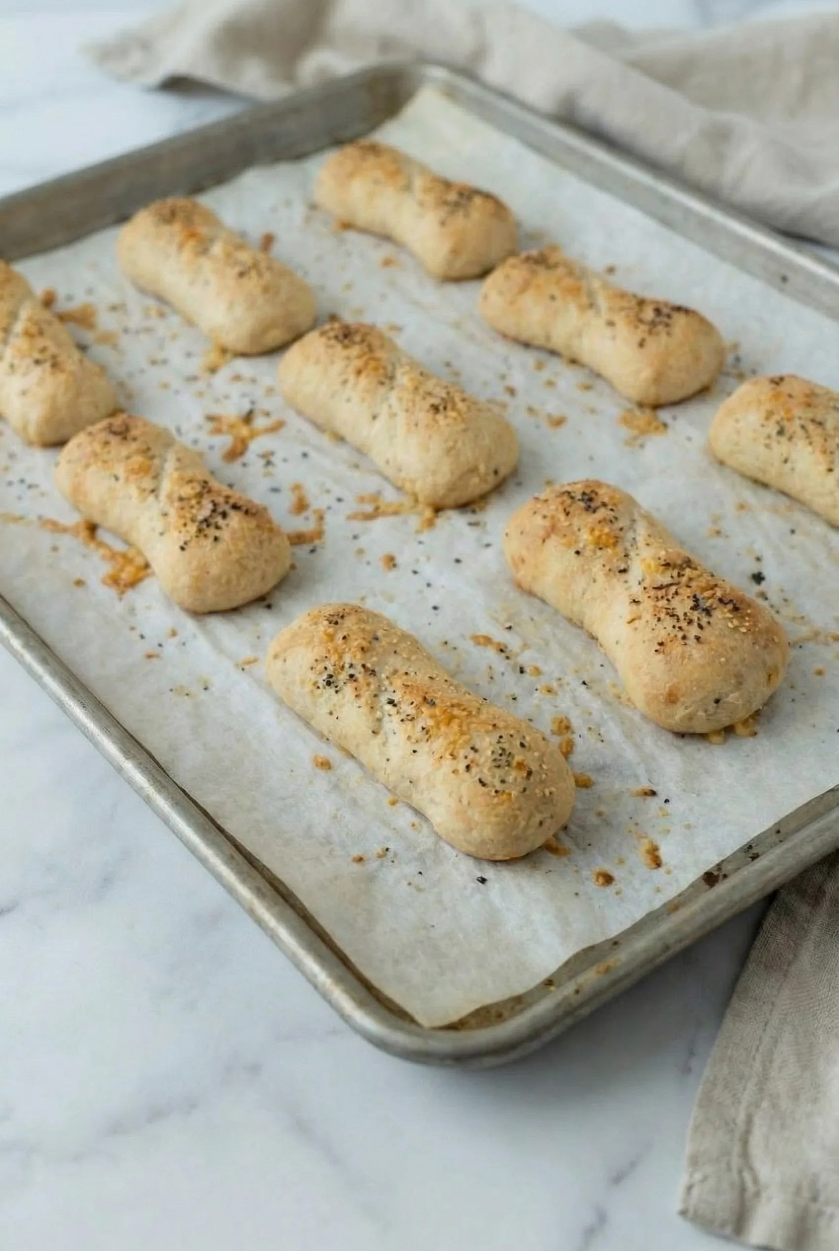 Freshly baked Homemade Pizza Sticks cooling on a baking tray with melted cheese spots