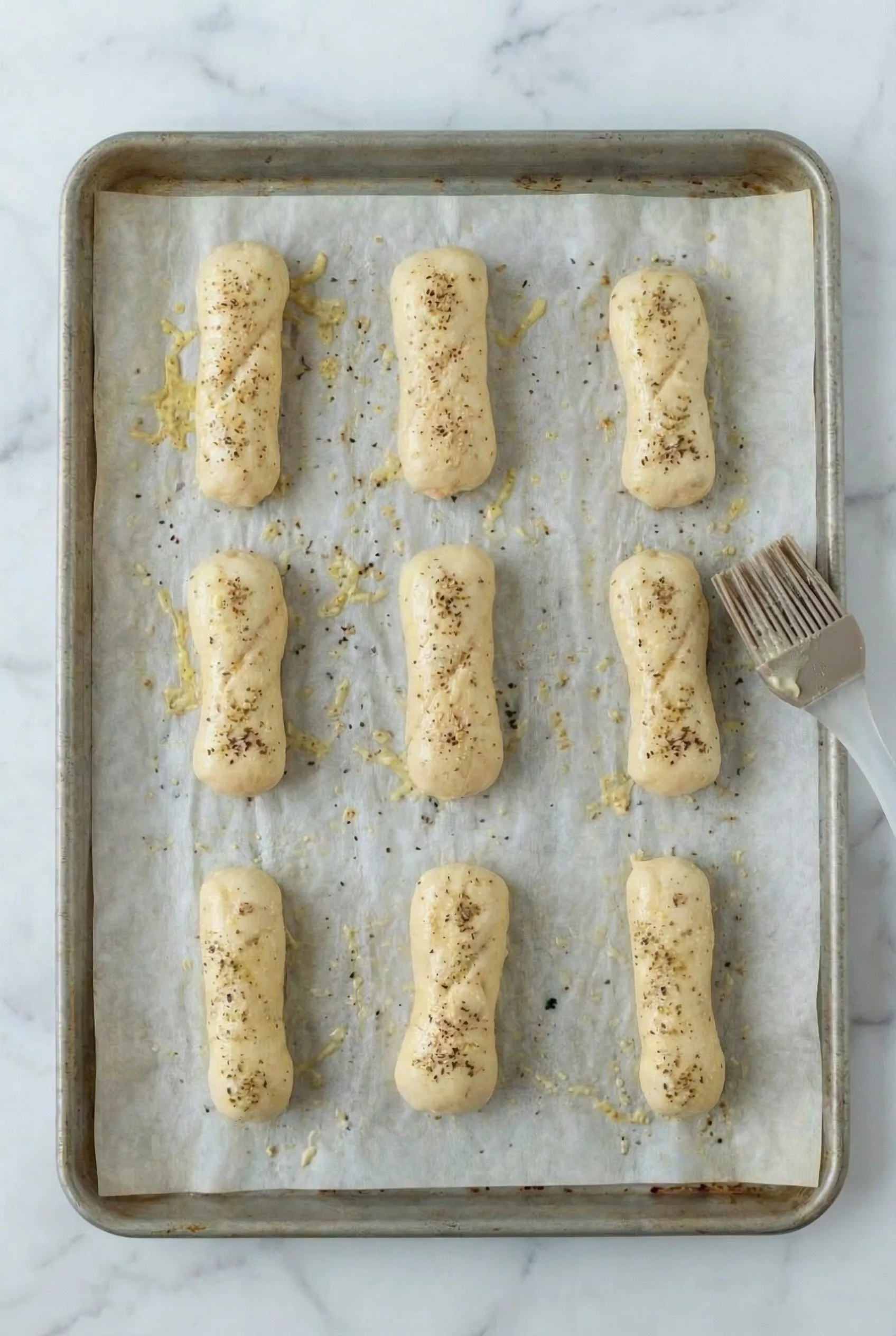 Unbaked pizza sticks brushed with melted butter and seasoning before baking