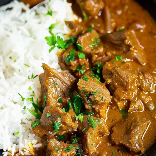 Close-up of a hearty beef curry cooked to perfection, served alongside fluffy white rice.