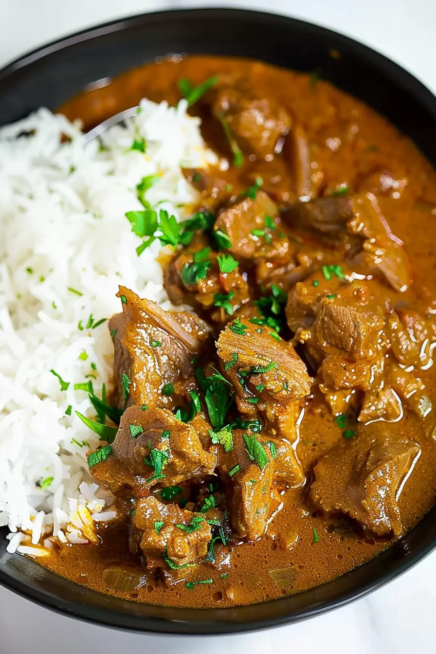 Close-up of a hearty beef curry cooked to perfection, served alongside fluffy white rice.