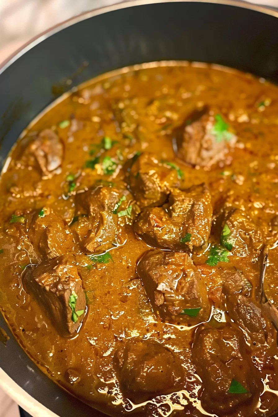 Slow-cooked beef curry in a deep pot, garnished with freshly chopped parsley for a pop of color.