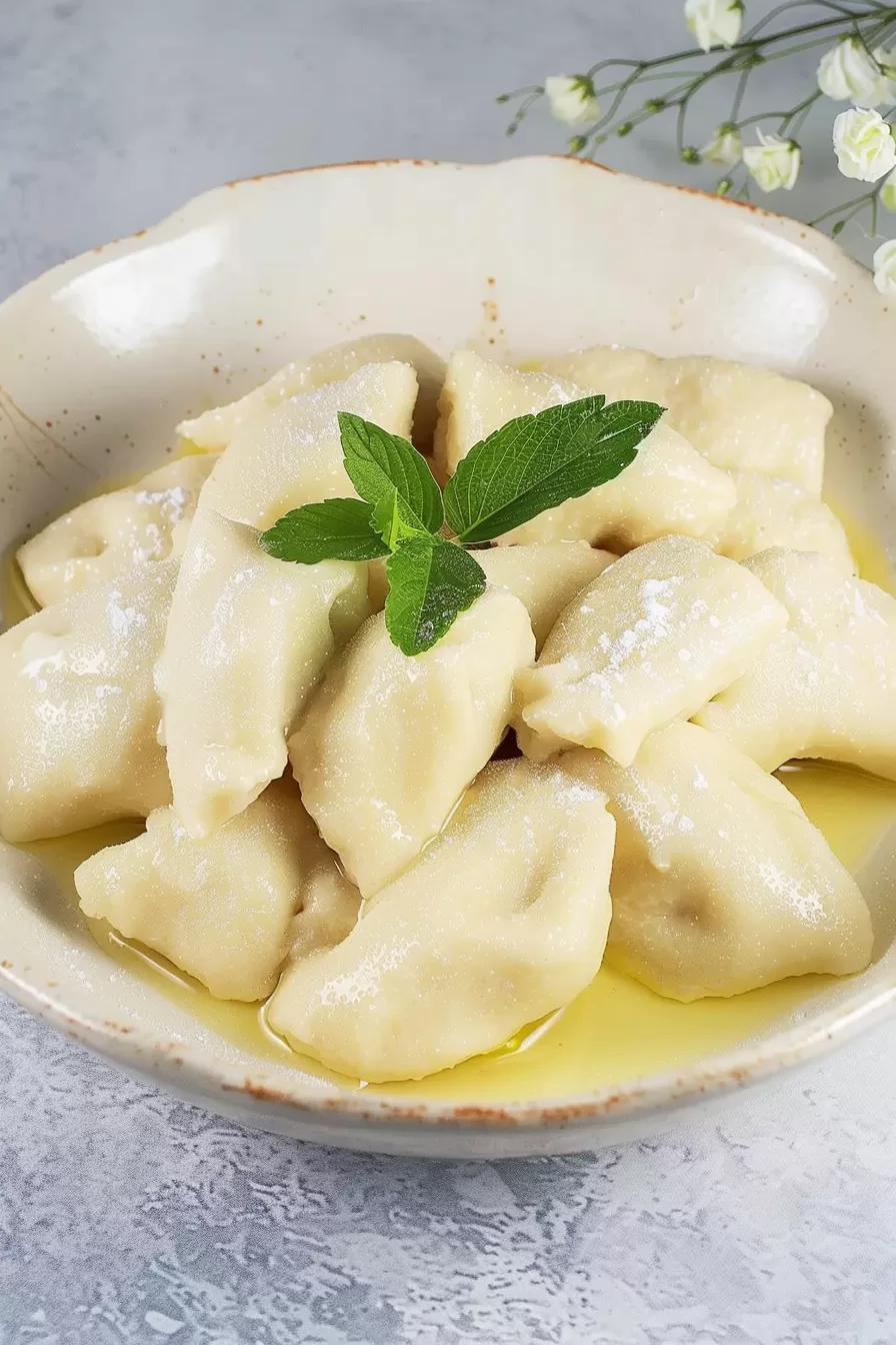 Close-up of golden butter-covered dumplings arranged neatly in a ceramic dish.