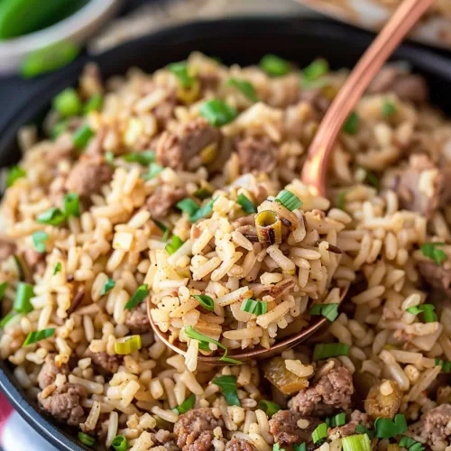 A spoonful of savory Louisiana Dirty Rice being served from a cast-iron skillet, highlighting its rustic presentation.