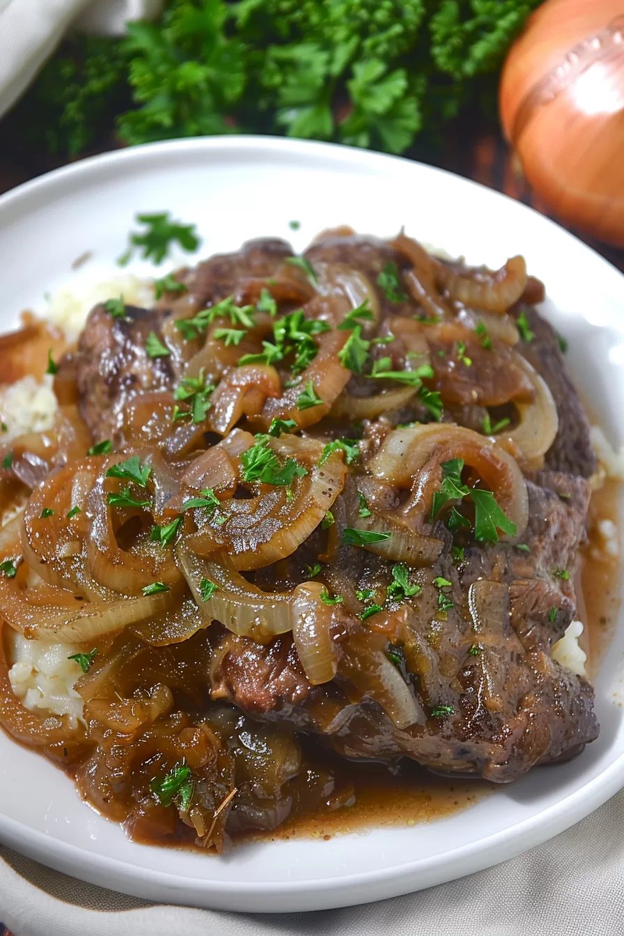 Tender liver smothered in caramelized onions served on a white plate, garnished with fresh parsley.