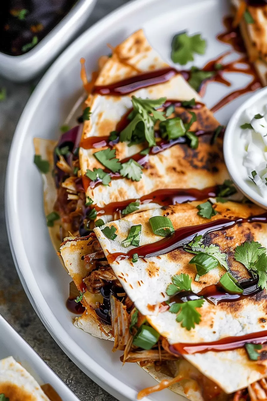 Perfectly grilled pork carnitas quesadilla, layered with gooey cheese and slow-cooked pork, topped with sour cream and cilantro.