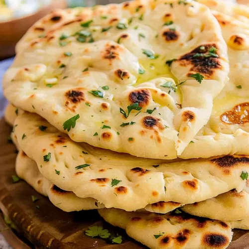 Roti bread with a golden-brown finish, brushed with melted butter and sprinkled with fresh herbs on a wooden platter.