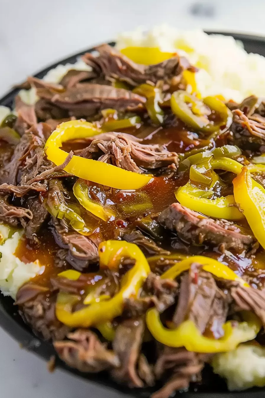 Shredded Mississippi-style beef served over mashed potatoes, with a drizzle of gravy and sliced yellow peppers.