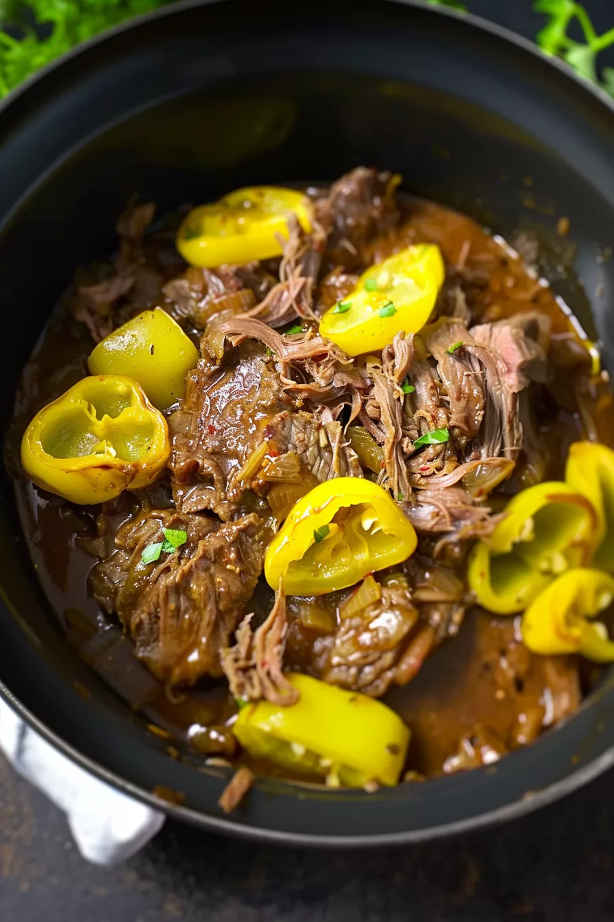 A bowl of shredded beef roast mixed with pepperoncini and onions, highlighting the tenderness of the meat.